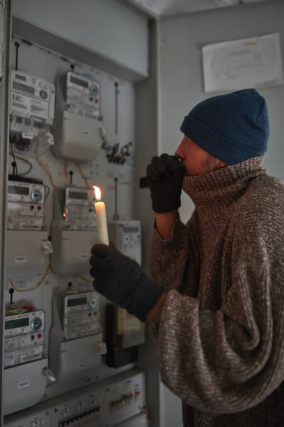 istock Checking the electricity power meter with a candle in cold winter days while there is power outage. 2192368083