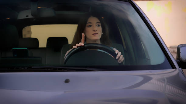 istock Young woman hesitating and pointing finger up while driving car 2192368917