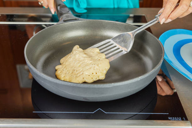 A close-up of a person flipping a pancake in a frying pan, ensuring even cooking for a golden-brown breakfast.
