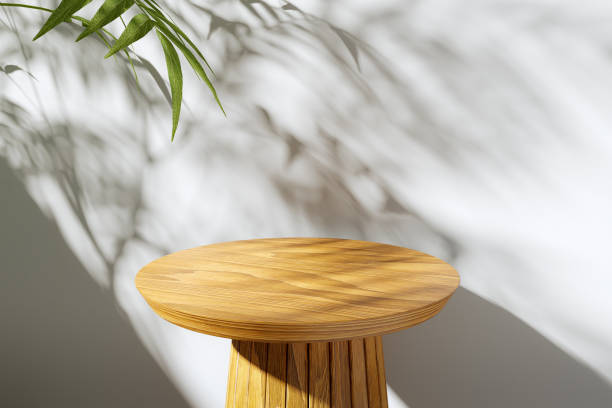 istock Close-up of a round wooden modern table. White background illuminated by sunlight. Shadow from the leaves on the wall. Background for product presentation. Mock up. Podium. 2192372101