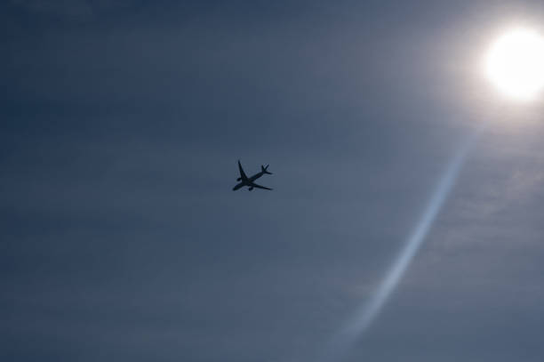 An airplane from below with lots of sky and bright sun