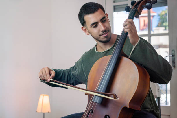 istock Young musician playing cello indoors with bow and strings 2192381724