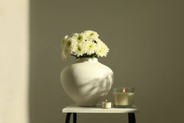 istock Evening still life. Flower bouquet in bowl and burning candle on beige interior. Selective soft focus. Minimalist still life. Light and shadow nature background. 2192382643
