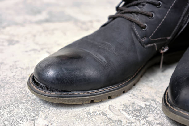 istock Close-up a a black leather torn old boots on tiled floor. 2192384287