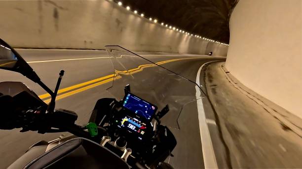 “Dynamic image captured from a motorcyclist’s point of view navigating a curved tunnel, with the digital dashboard in focus and well-lit curves ahead. Perfect for projects on adventure, motorcycle travel, technology, and mobility.”