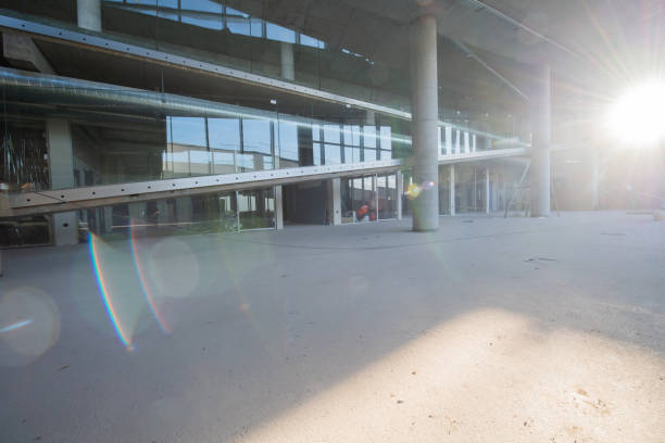 A captivating view of a modern business building under construction, showcasing its raw industrial interior with exposed steel beams and concrete walls bathed in the warm, golden hues of a sunset.