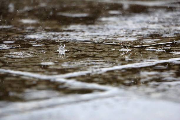 istock a closeup of raindrops falling into a puddle and splashing a crown 2192390656