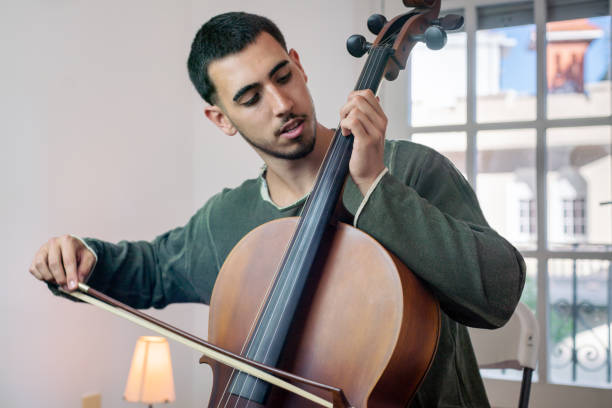 istock Young man playing cello, practicing at home near window 2192395741