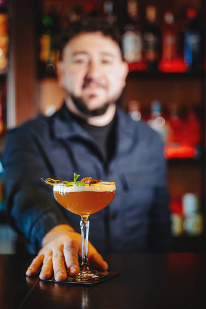 istock Portrait of a handsome bartender serving an alcoholic cocktail at the bar. Selective focus on cocktail 2192397331