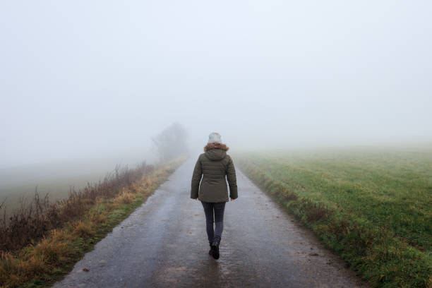 istock Lonely woman walk on empty road in mist 2192399365
