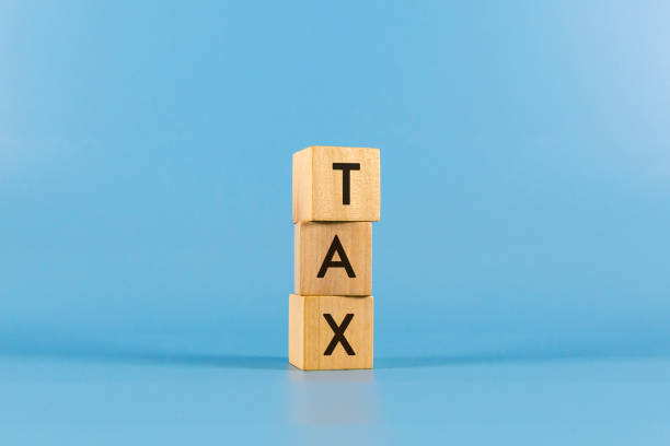 istock TAX text on wooden block with blue backgrounds. 2192399410