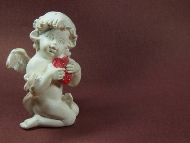 A white angel hugs a heart. Figurine. Love, greeting card. Invitation.