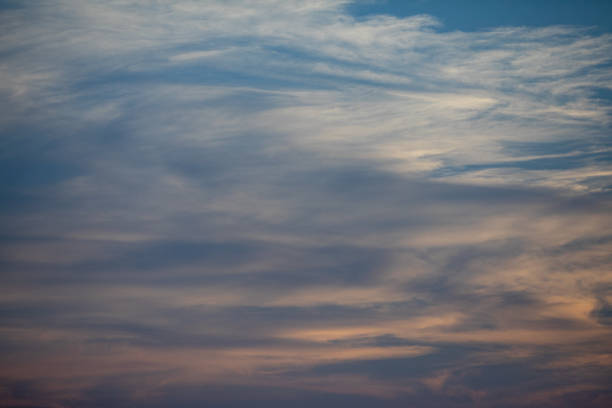 A tranquil evening sky painted in soft, gentle hues, showcasing delicate wispy clouds at a beautiful twilight