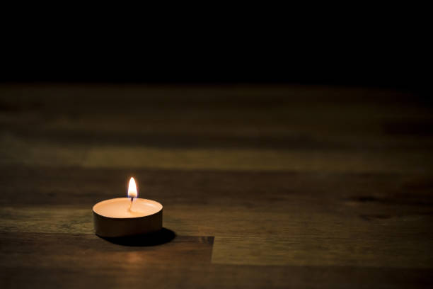 Small white tea candle on a wooden table, close up shot. Tealight ambiance concept.