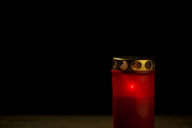 Red cemetery candle, on a black background, close up shot. All saints day concept.