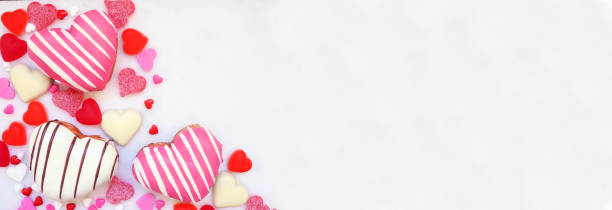 istock Valentines Day heart shaped sweets corner border with donuts and candies on a white marble banner background 2192414588
