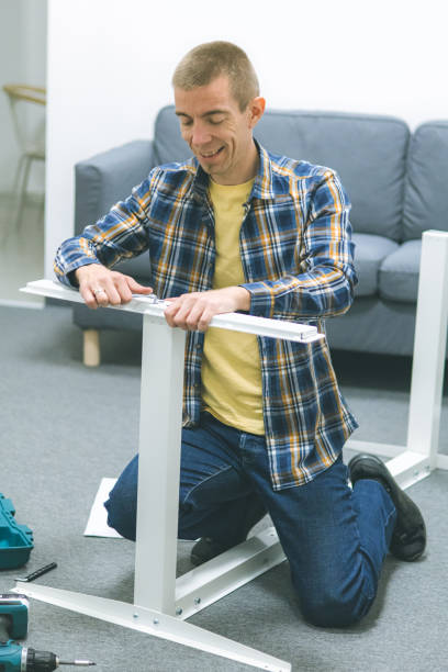 istock Mid adult craftsman assembling furniture on the floor inside modern office workspace, using hand tools. 2192414594