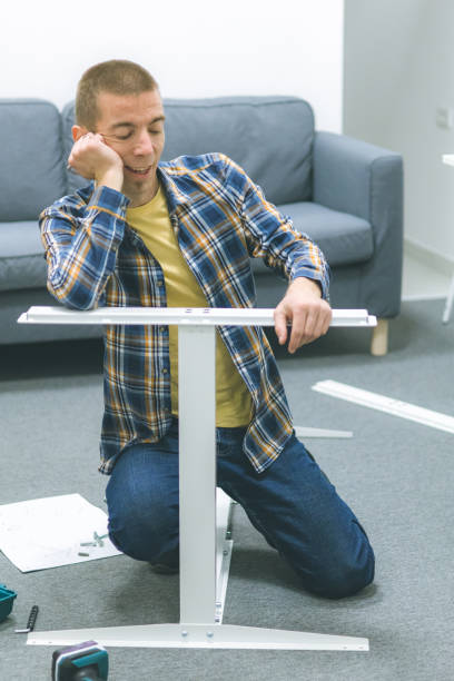 istock Mid adult craftsman assembling furniture on the floor inside modern office workspace, using hand tools. 2192414651