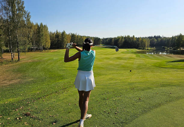 Golfer preparing to swing on a sunny day at a lush golf course surrounded by trees