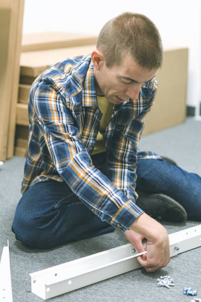 istock Mid adult craftsman assembling furniture on the floor inside modern office workspace, using hand tools. 2192415036