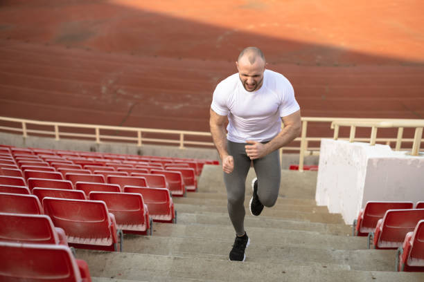 Man in athletic attire climbing stadium stairs as part of a fitness workout. The image captures dedication, effort, and the pursuit of physical health and well-being in a sports environment.