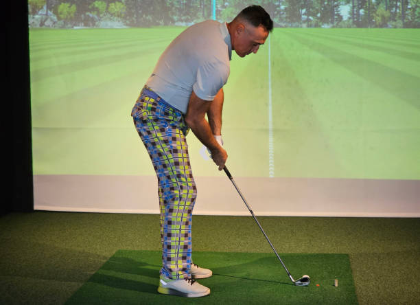 istock Golf player practicing swing indoors at virtual driving range with colorful plaid pants 2192415326
