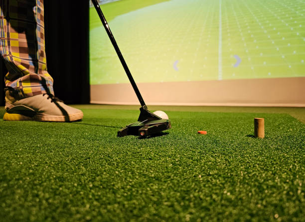 istock Golfer prepares to putt on artificial turf with virtual course display in background 2192415350