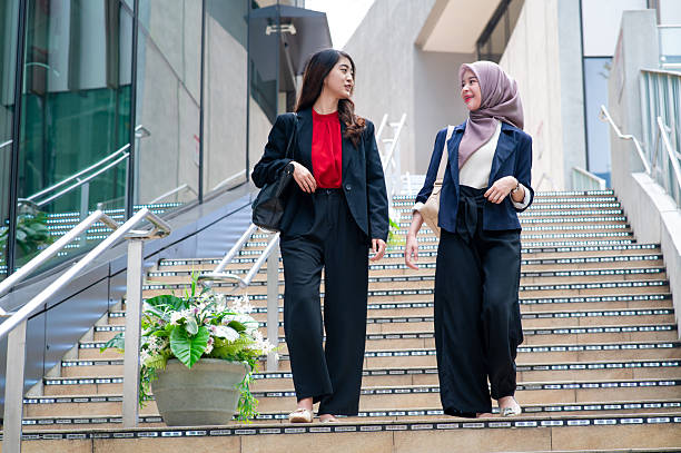 istock Two young female office colleagues having discussion while walking down a staircase 2192417366