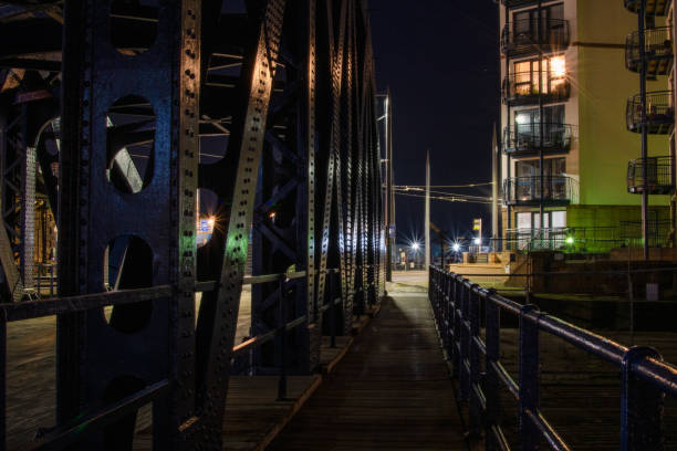 Steel structure of an old rail bridge and a footpath with metal handrail, residential buildings