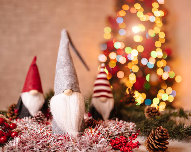Multiple ceramic gnome figures displayed together with spruce branches, forming a playful and heartwarming Christmas still life. Their colorful hats and winter motifs enhance the festive charm, making this image ideal for holiday campaigns, product presentations, or seasonal décor inspiration.