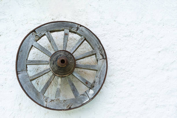 istock Old wooden wheel hanging on white wall representing history and tradition 2192423842