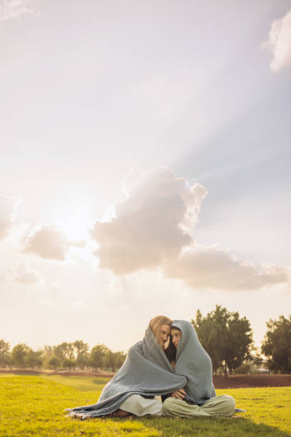 A DSLR photo of hands making a heart shape with the sun with beautiful sunbeams inside. Space for copy.