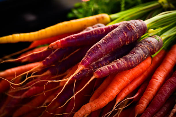 Bunches of whole raw multicolored Rainbow carrots on table at farmers market