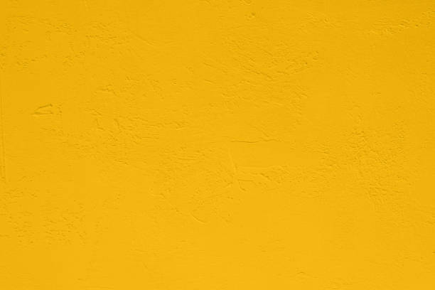 Saturated pastel yellow colored low contrast Concrete textured background. Empty colourful wall texture with copy space for text overlay and mockups. 2023, 2024 color trend