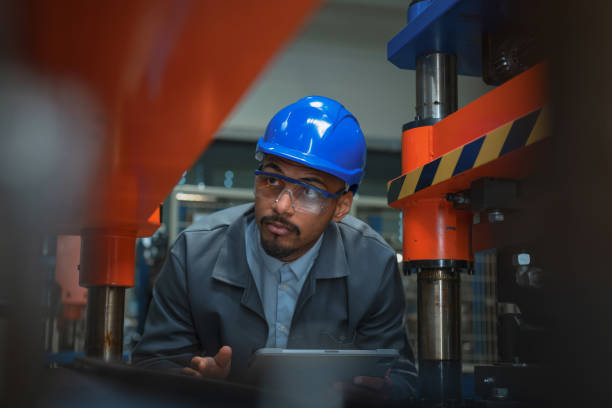 istock Engineer with a blue helmet and safety glasses, checking manufacturing machinery 2192435304