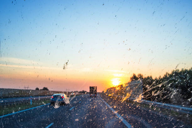Highway view at sunset through a dirty windshield, emphasizing road safety and the challenges of visibility while driving on long journeys. Transportation, logistics, road traffic. Copy space