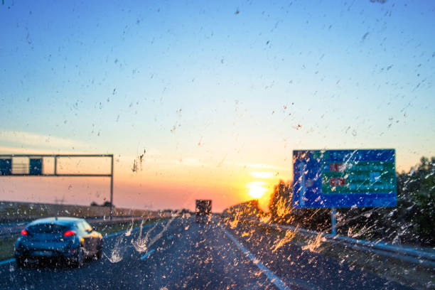 Blurry windshield sunset scene on a highway with cars and navigating signs, symbolizing navigation, transportation, logistics, road traffic. Poznan, Lodz, Wroclaw, Poland, A2, E30. Copy space