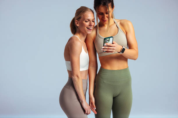 istock Two fit women sharing a laugh while looking at smartphone 2192441061