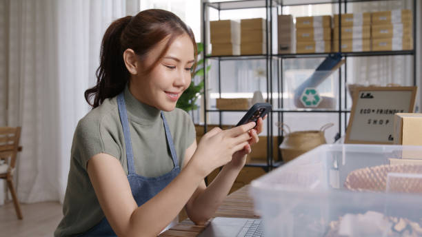 istock Go green SME owner reply chat comment online talk or set up chatbot on phone. Young seller asia woman typing mobile at home office easy selling CRM platform for eco friendly shop retail net zero store 2192443482