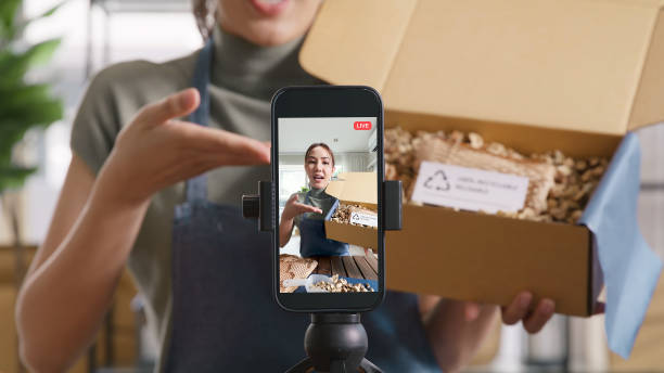 istock SME owner go green net zero retail store live stream talk on phone showing eco care plastic free packaging box. Asia people young woman record video on tiktok IG reel instagram shop happy side hustle. 2192443599