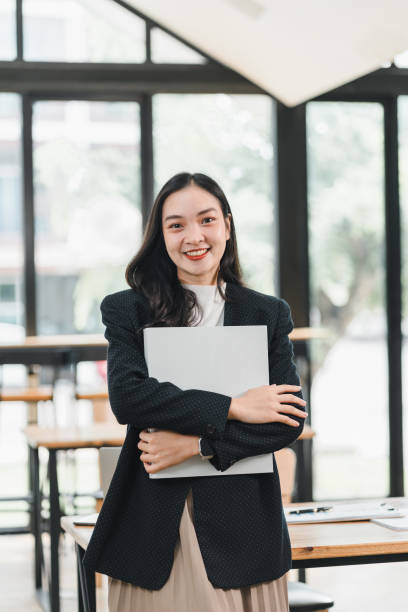 istock confident woman in blazer holds laptop while smiling in modern office space. Her professional demeanor reflects positive work environment 2192450196