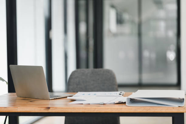 istock modern office workspace featuring laptop, documents, and binder on wooden desk. clean design promotes productivity and focus in professional setting 2192451789