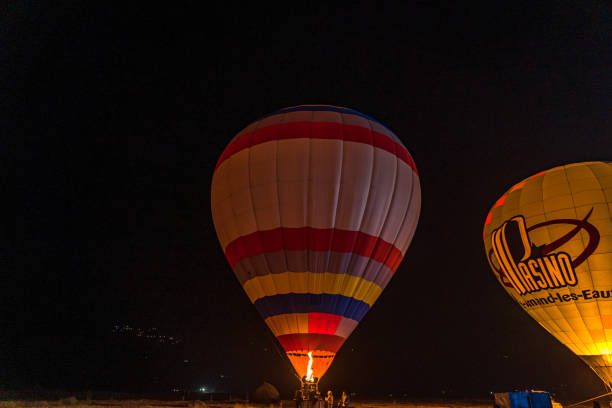 A hot air balloon launces from a beach watched by curious bystanders