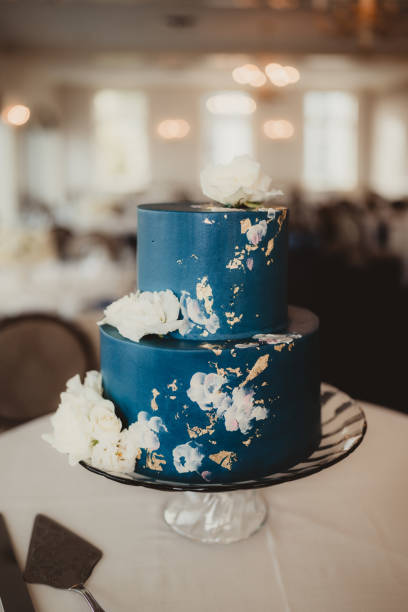 Blue layered wedding cake with gold leaf decoration and flowers