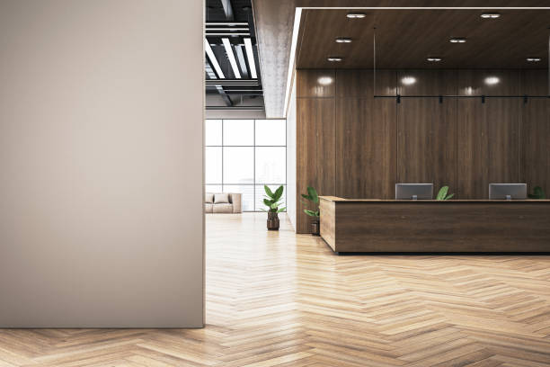 istock Modern reception area with wooden desk and chevron-patterned flooring, bright window view, and clean wall space for branding. 3D Rendering 2192466503