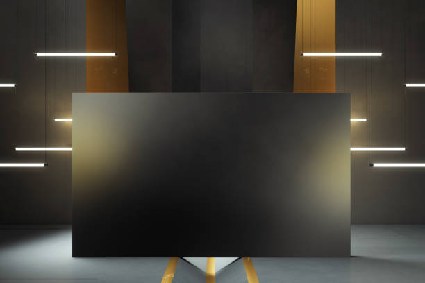 Black board on a wooden stand, surrounded by glowing hanging lights, dark walls, and gold accents in a stylish industrial setting, concept of modern design. 3D Rendering.