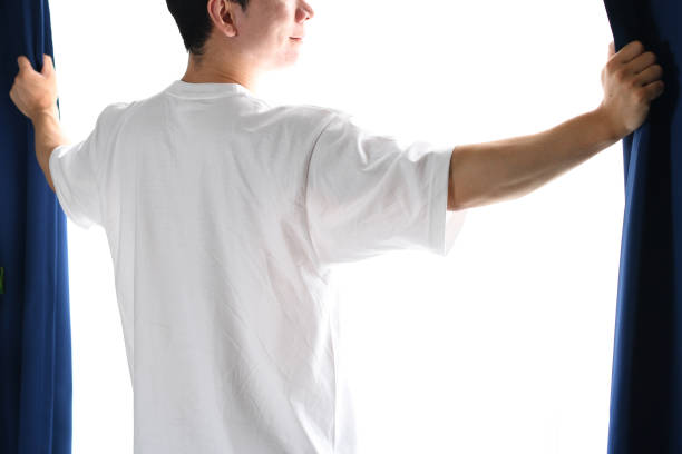 Asian man opening the curtains and soaking in the sunlight