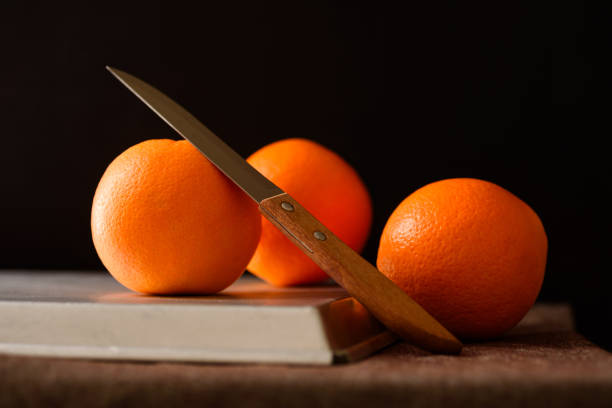 A man is cutting persimmons with a knife on a brown table, on a white plate you can see the movements of the knife on the product 1