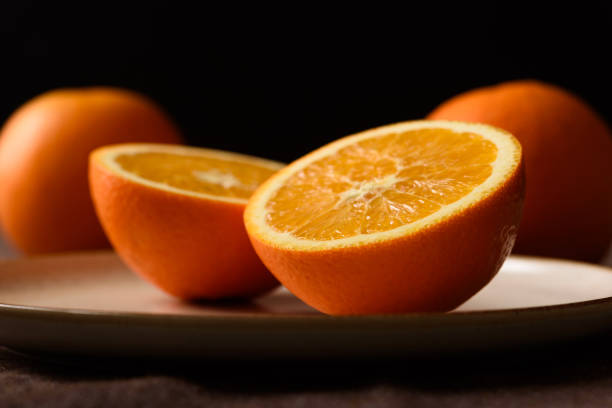 istock Fresh sliced navel oranges on brown ceramic plate on black background. Close up view. 2192468321