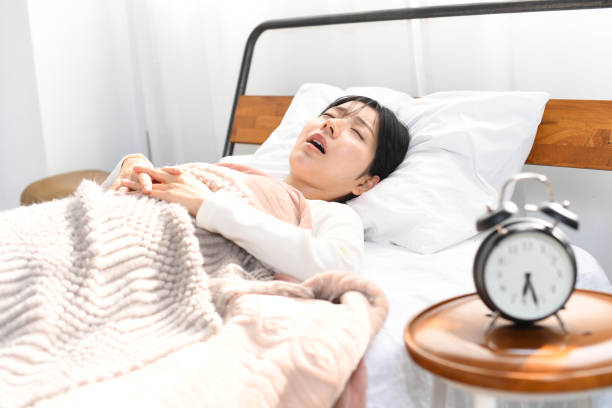 大きないびきをかきながらベッドで眠るアジアの若い女性 - 不眠症 ストックフォトと画像
